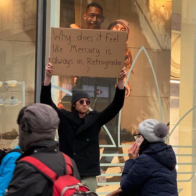 The meme is a humorous image of a person holding a sign that reads, "Why does it feel like Mercury is always in retrograde?" The phrase "Mercury in retrograde" is a common astrological term that refers to a period when the planet Mercury appears to be moving backwards in the sky, but the phrase has become a cultural phenomenon to describe any period of chaos or confusion.